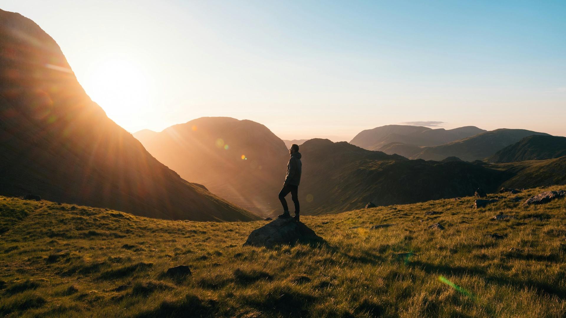 A person standing on the top of a mountain overlooking a horizon of clouds.