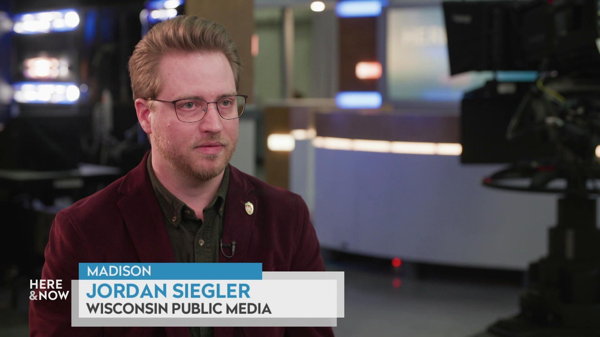  still image from a video shows Jordan Siegler seated in front of a film set with a graphic at bottom reading 'Madison,' 'Jordan Siegler' and 'Wisconsin Public Media.'