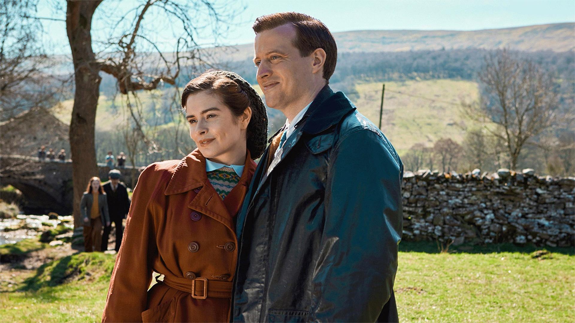 James and Helen together outdoors in the countryside, in coats and smiling