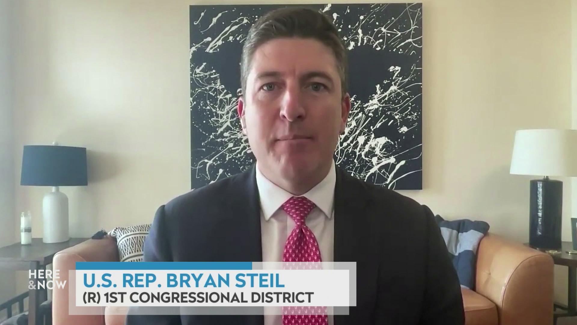 A still image shows Bryan Steil seated in front of a brown leather couch and a large black and white color splotch painting, with a graphic at the bottom that reads 'U.S. Rep. Bryan Steil' and '(R) 1st congressional district.'