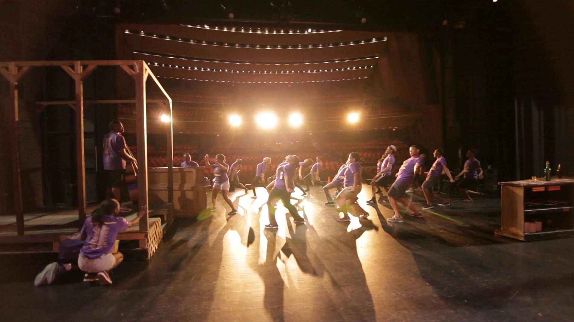 The cast of "The Color Purple" on stage in purple shirts.