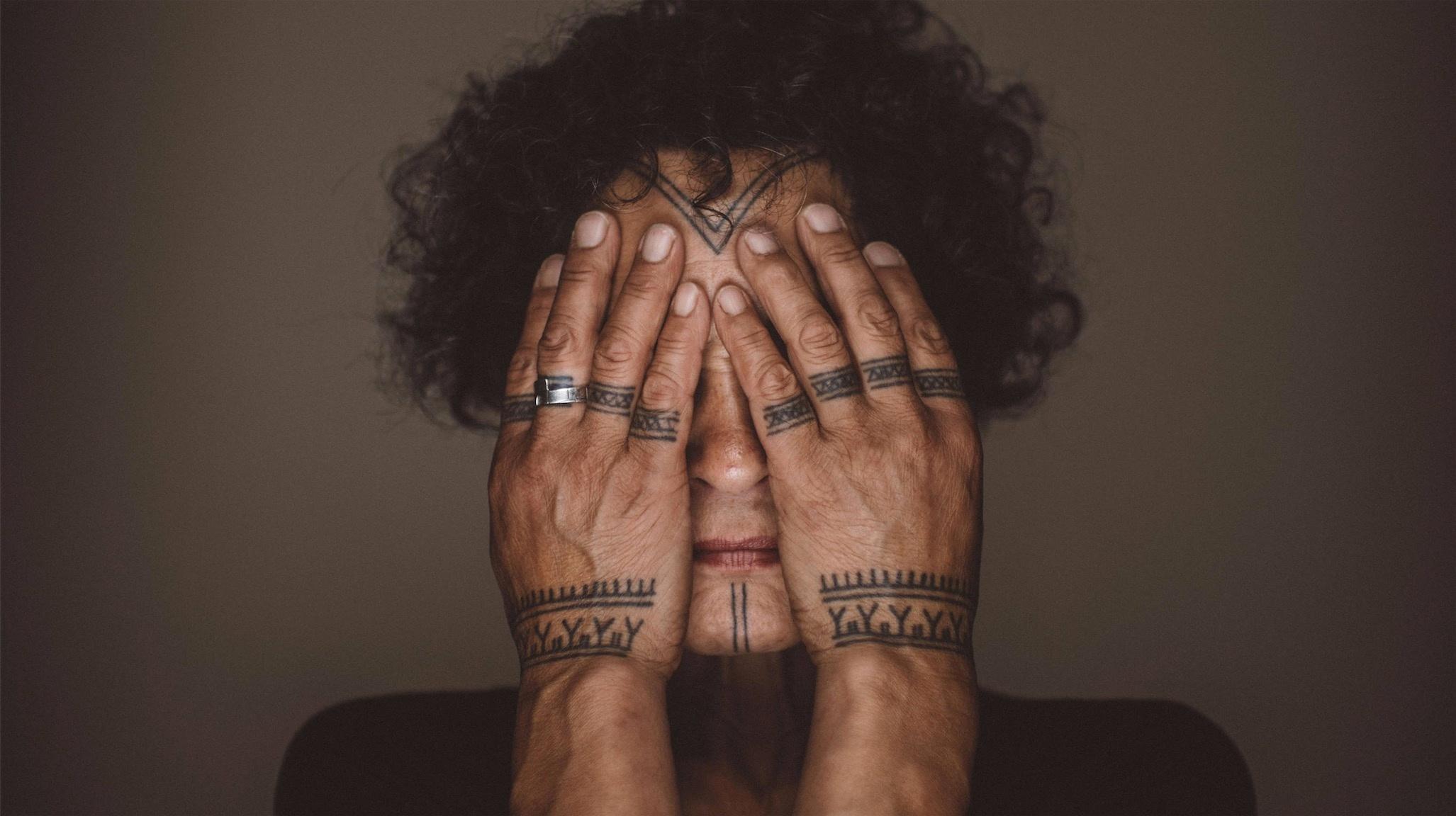 Aaju Peter with her tattooed hands covering her face.