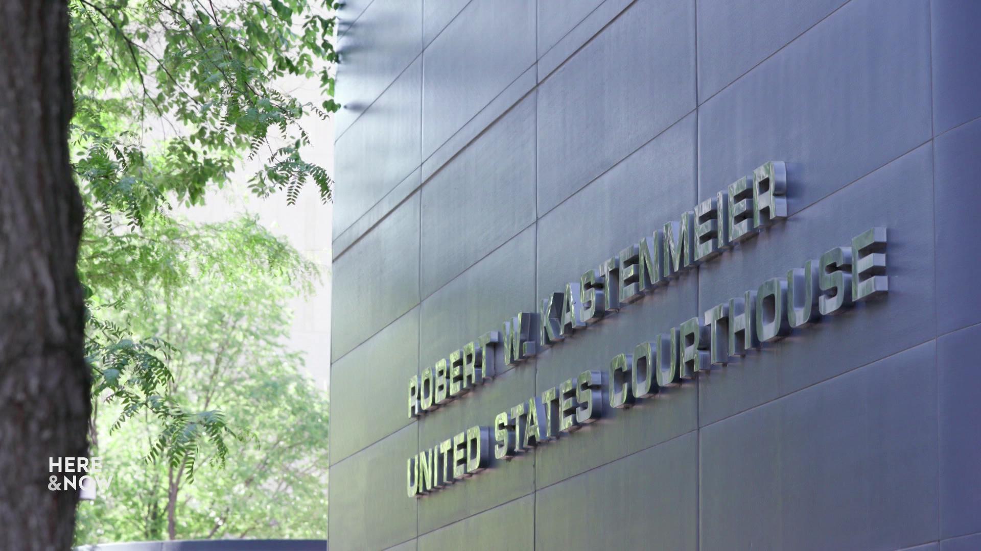 A still image shows a tall metal wall with the words Robert W. Kastenmeier United States Courthouse on it.