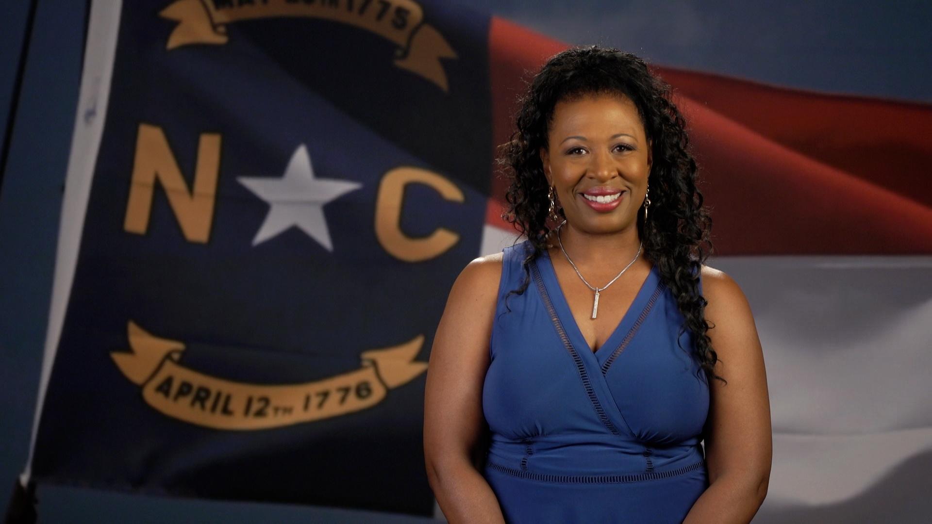Deborah Holt Noel in front of the North Carolina state flag.