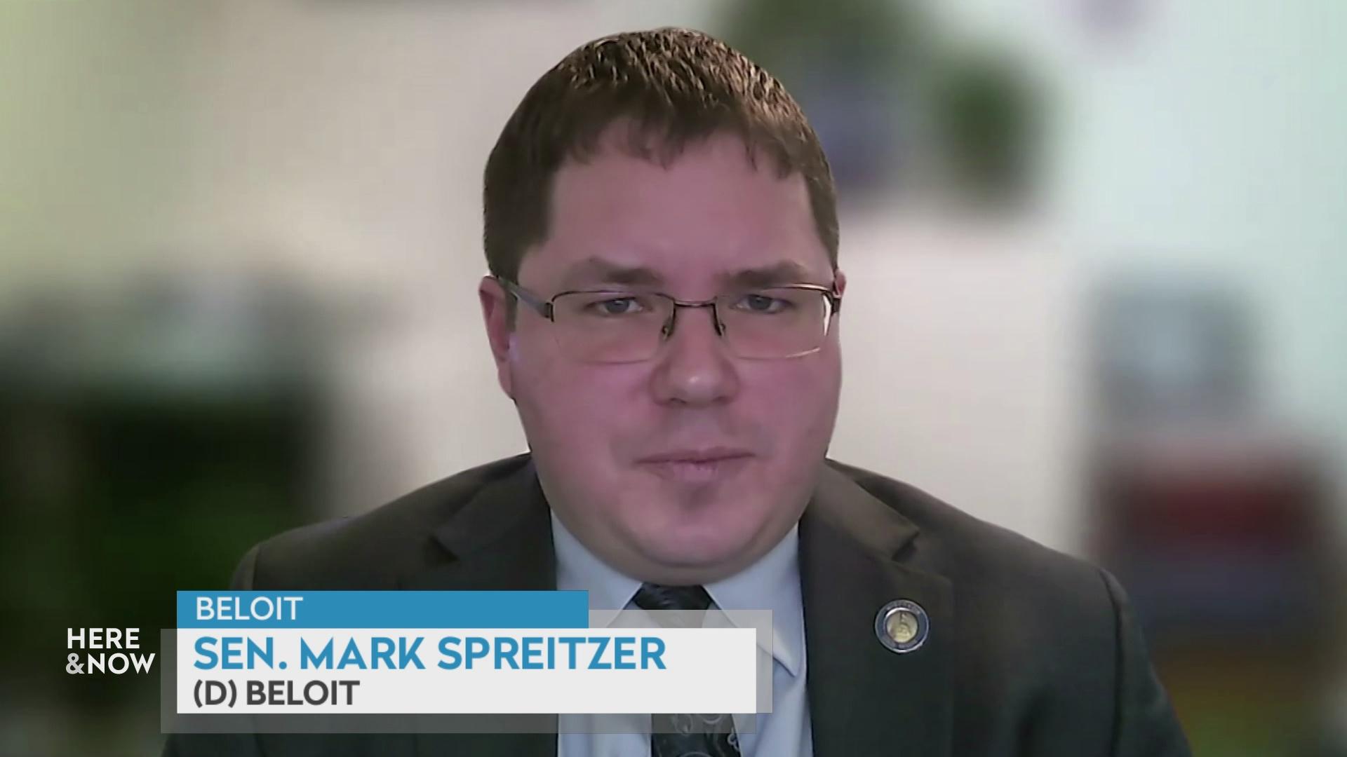 A still image from a video shows Mark Spreitzer seated in front of a blurred background with a graphic at bottom reading 'Beloit,' 'Mark Spreitzer' and '(D) Beloit.'