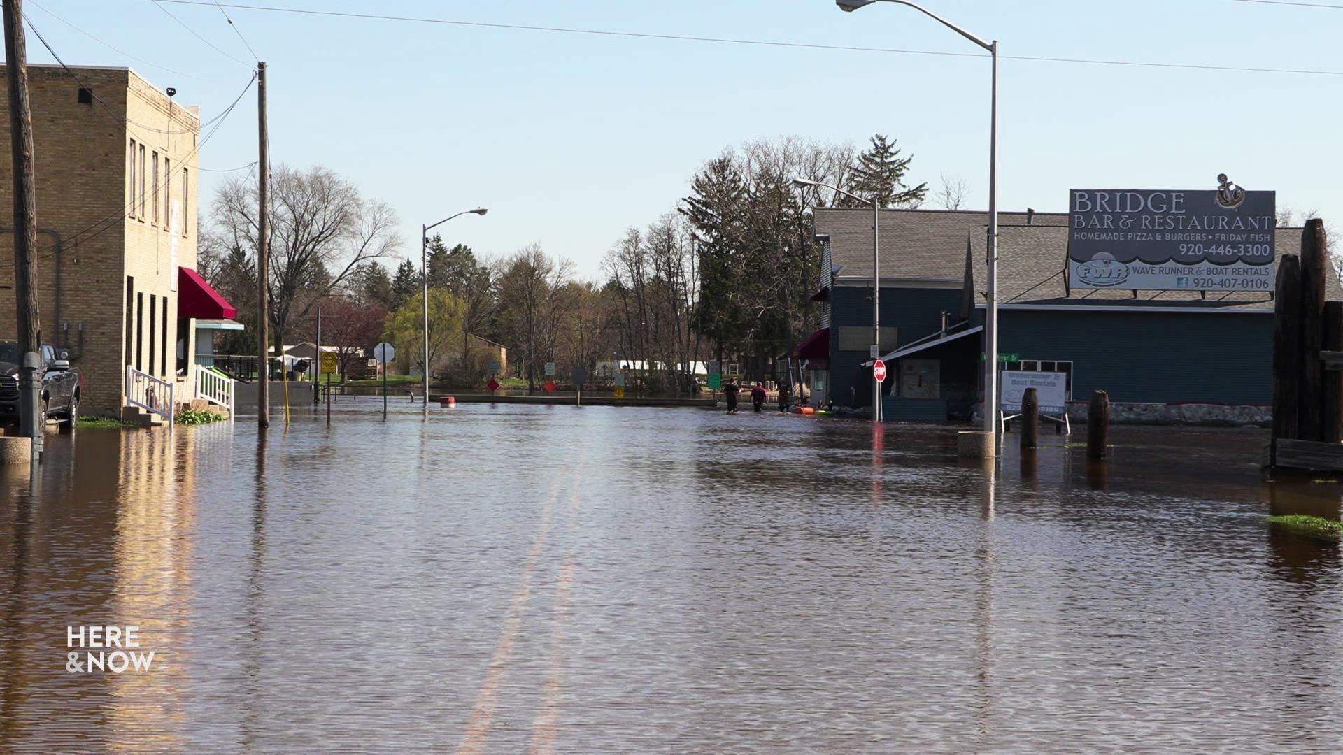 A still image shows a street in downtown Fremont flooded with knee-deep water.