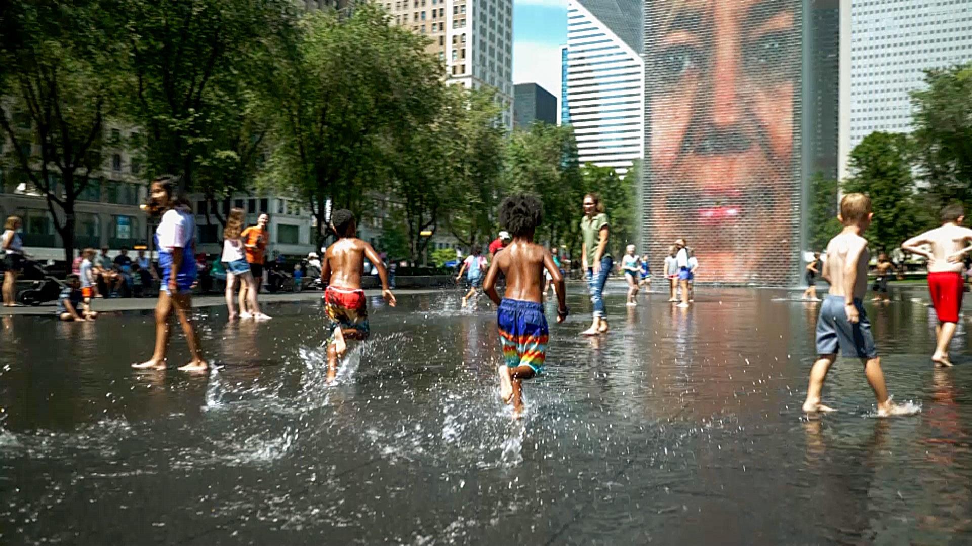 Children in swimsuits running through water in Millennium Park