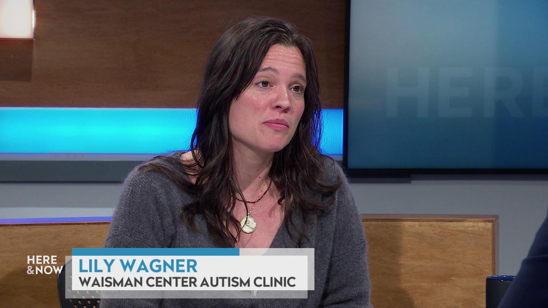 A still image shows Lily Wagner seated at the 'Here & Now' set featuring wood paneling, with a graphic at bottom reading 'Lily Wagner' and 'Waisman Center Autism Clinic.'
