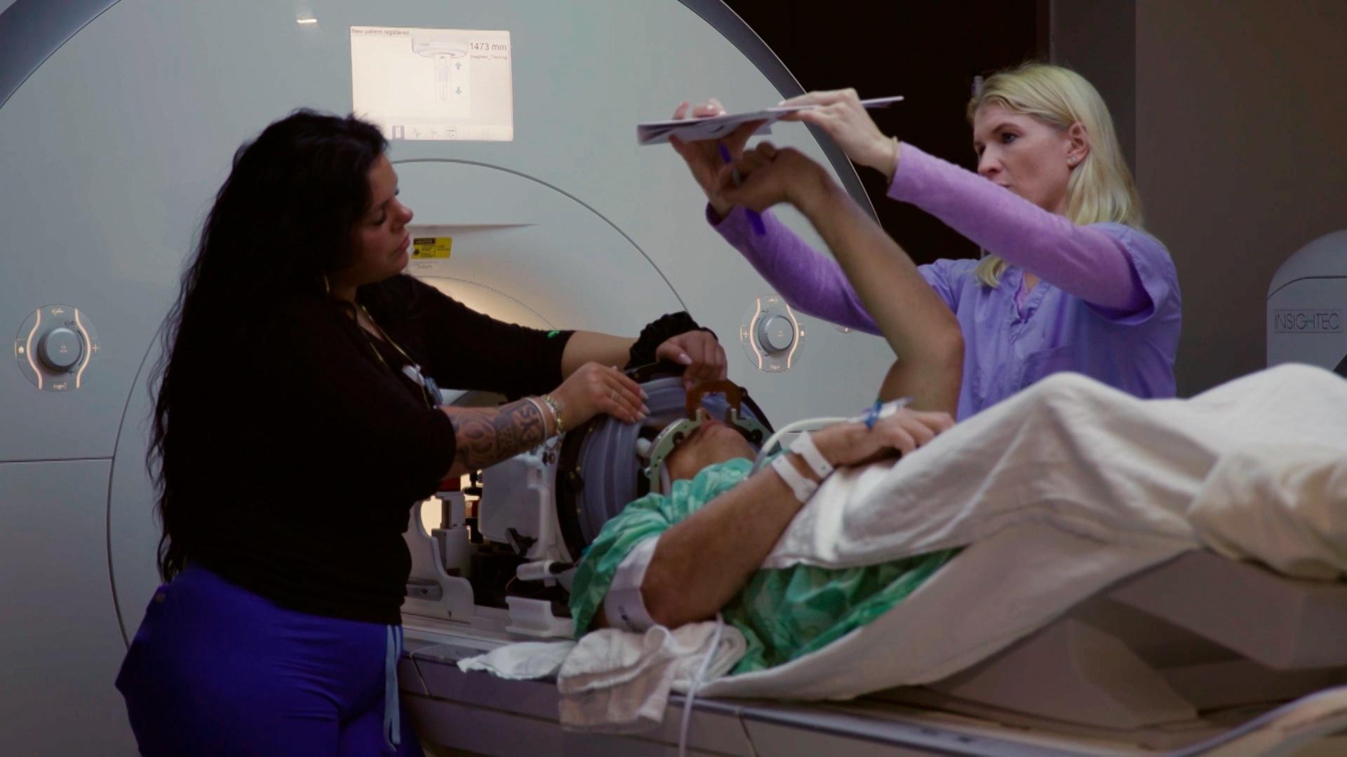 Two doctors examining someone on an MRI table.