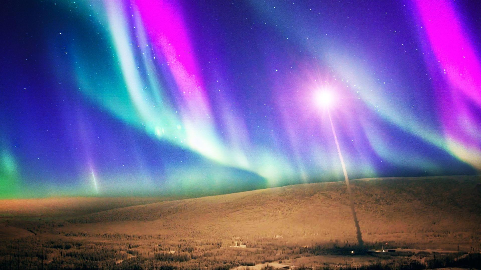 The aurora borealis above a hill and street light.