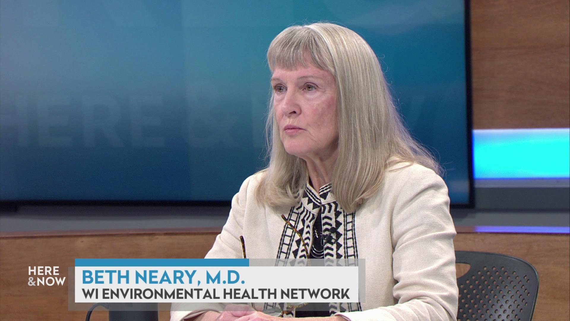 A still image shows Dr. Beth Neary seated at the 'Here & Now' set featuring wood paneling, with a graphic at bottom reading 'Beth Neary, M.D.' and 'Wi. Environmental Health Network.'