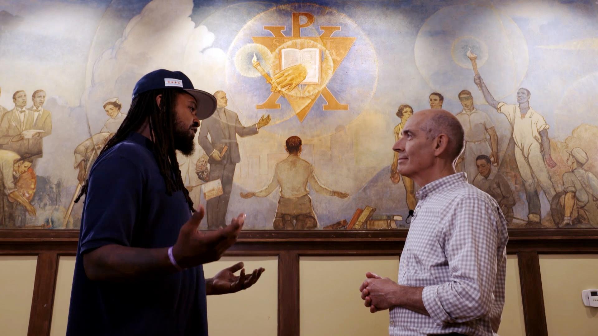 Geoffrey Baer talking with Shermann Thomas in front of mural
