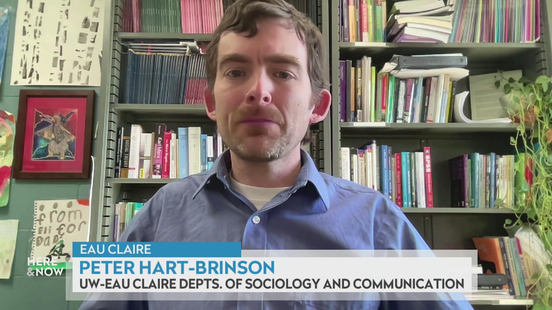A still image from a video shows Peter Hart-Brinson seated in front of a shelves lined with books with a graphic at bottom reading 'Eau Claire,' 'Peter Hart-Brinson' and 'Eau Claire Dept. of Sociology and Communication.'
