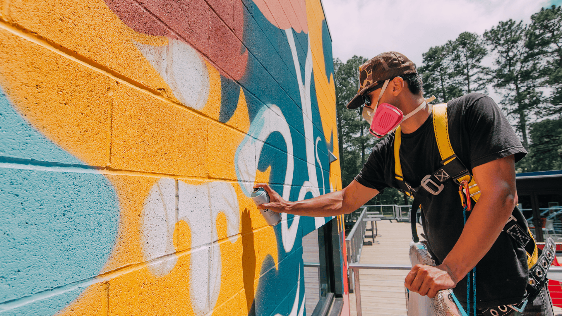 Muralist Gabriel Eng-Goetz spray painting a mural with protective gear on.