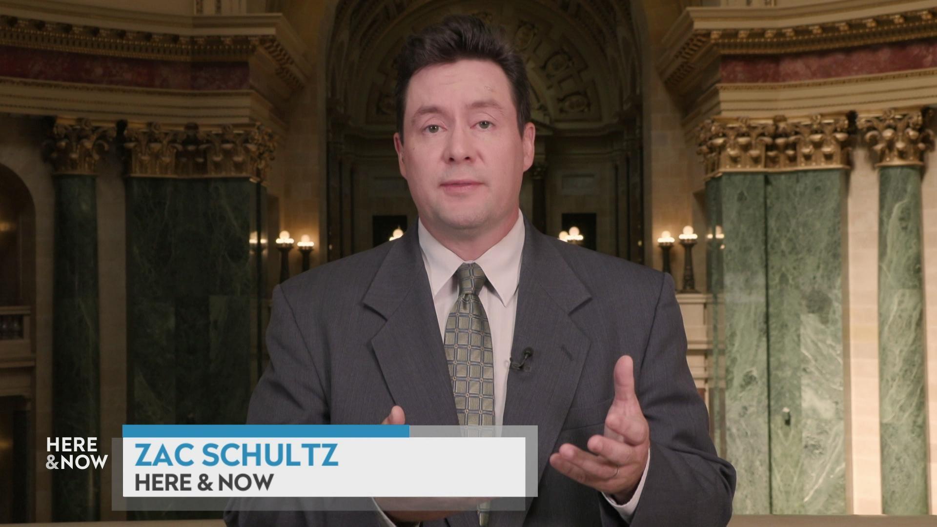 Zac Schultz stands in front of the State Capitol rotunda indoors with green marble walls and white columns with a graphic at bottom reading 'Zac Schultz' and 'Here & Now.'