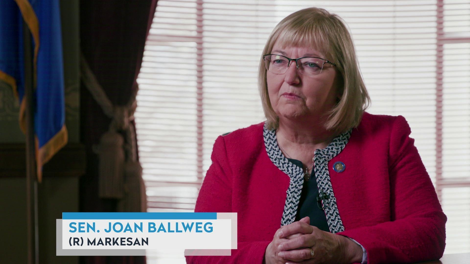 A still image from a video shows Joan Ballweg seated to the right of a Wisconsin state flag, with a graphic at bottom reading 'Sen. Joan Ballweg' and '(R) Markesan.'