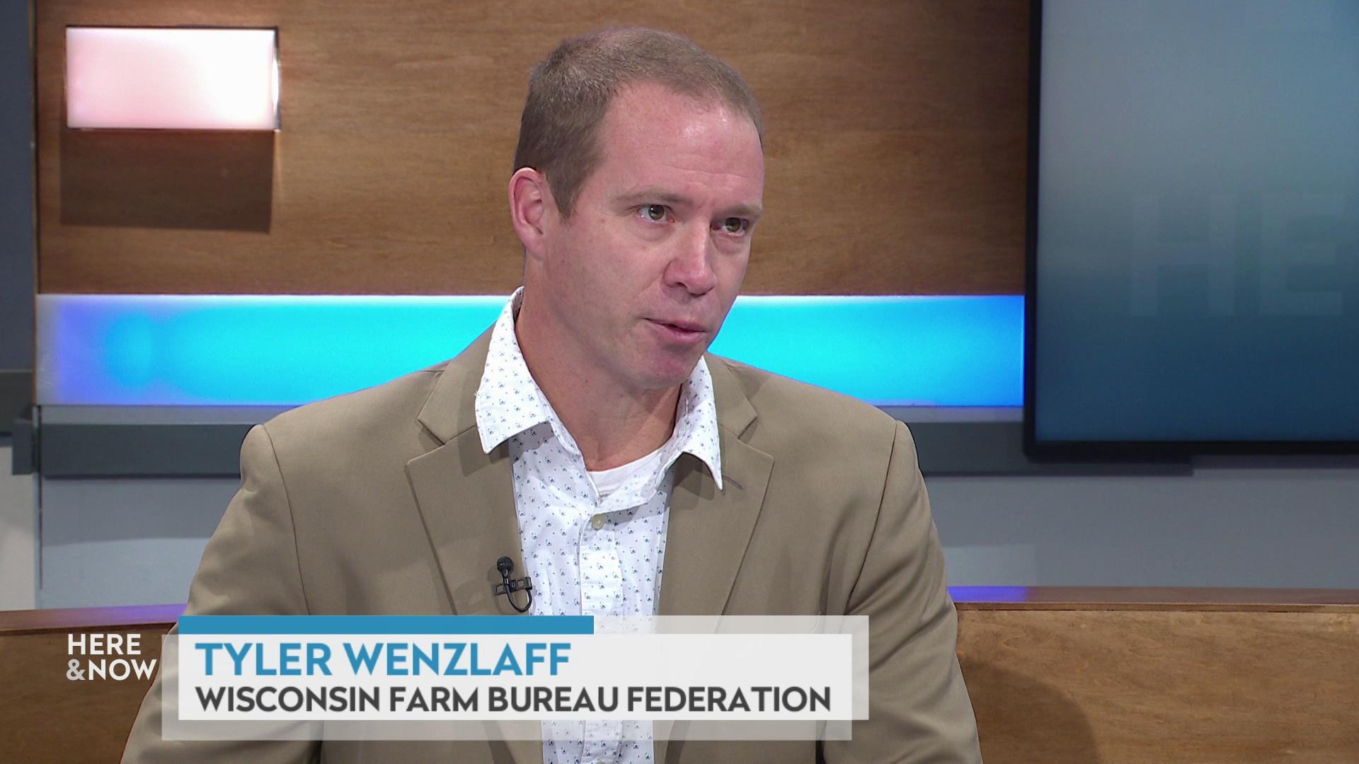 A still image shows Tyler Wenzlaff seated at the 'Here & Now' set featuring wood paneling, with a graphic at bottom reading 'Tyler Wenzlaff' and 'Wisconsin Fair Bureau Federation.'