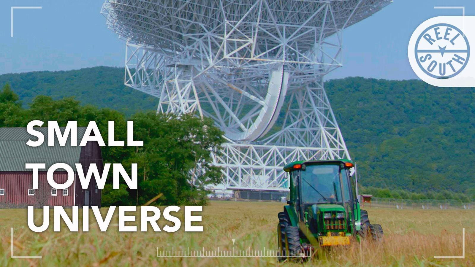 A radio telescope behind a red bard and green tractor. 