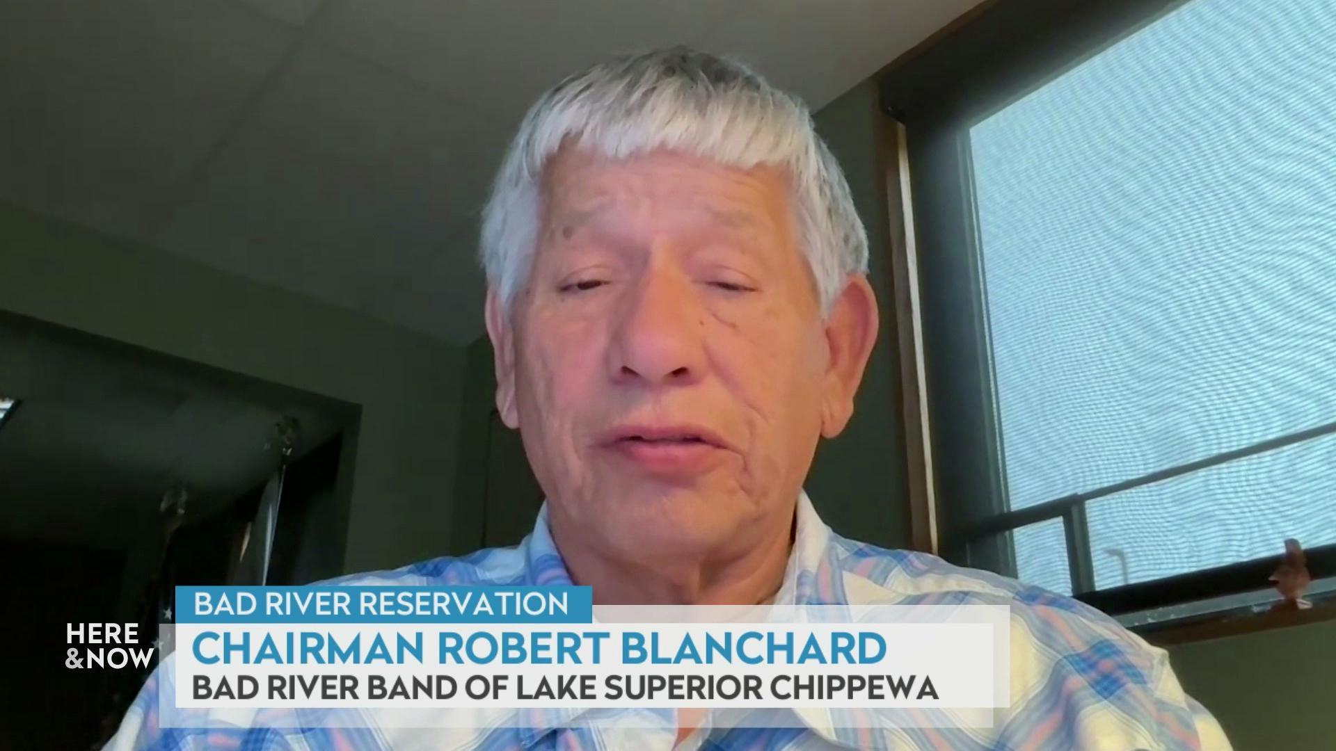 A still image shows Robert Blanchard seated in a room with green walls, with a graphic at the bottom that reads 'Bad River Reservation,' 'Chairman Robert Blanchard' and 'Bad River Band of Lake Superior Chippewa.'