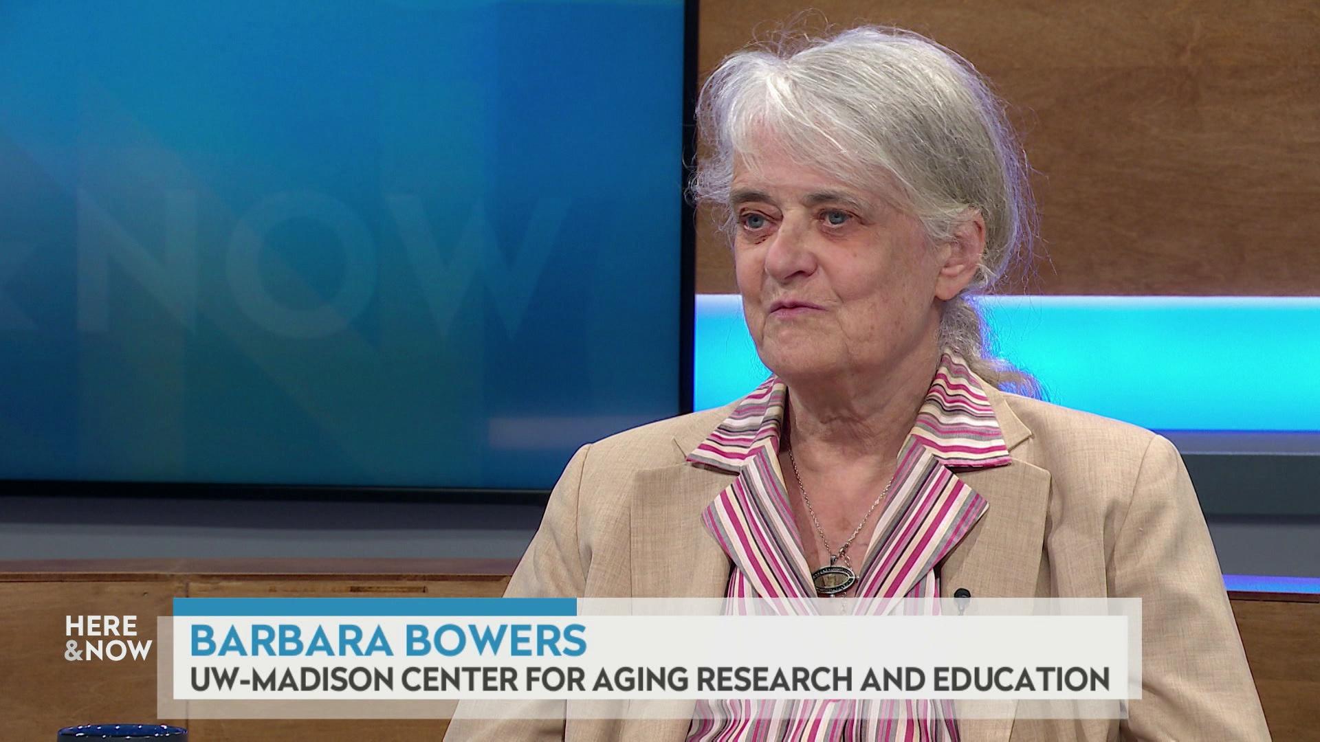 A still image shows Barbara Bowers seated at the 'Here & Now' set featuring wood paneling, with a graphic at bottom reading 'Barbara Bowers' and 'UW-Madison Center for Aging Research and Education.'