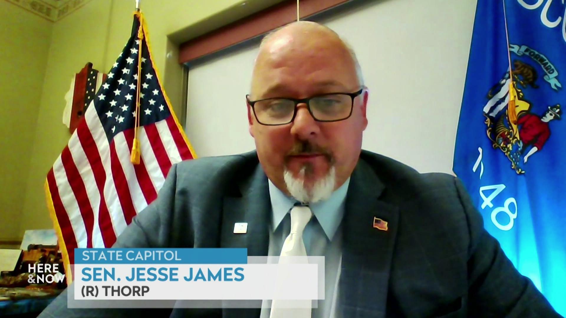 A still image shows state Senator Jesse James seated in front of a U.S. flag and a Wisconsin flag, with a graphic in the bottom reading 'State capitol,' 'Sen. Jesse James' and '(R) Thorp.'