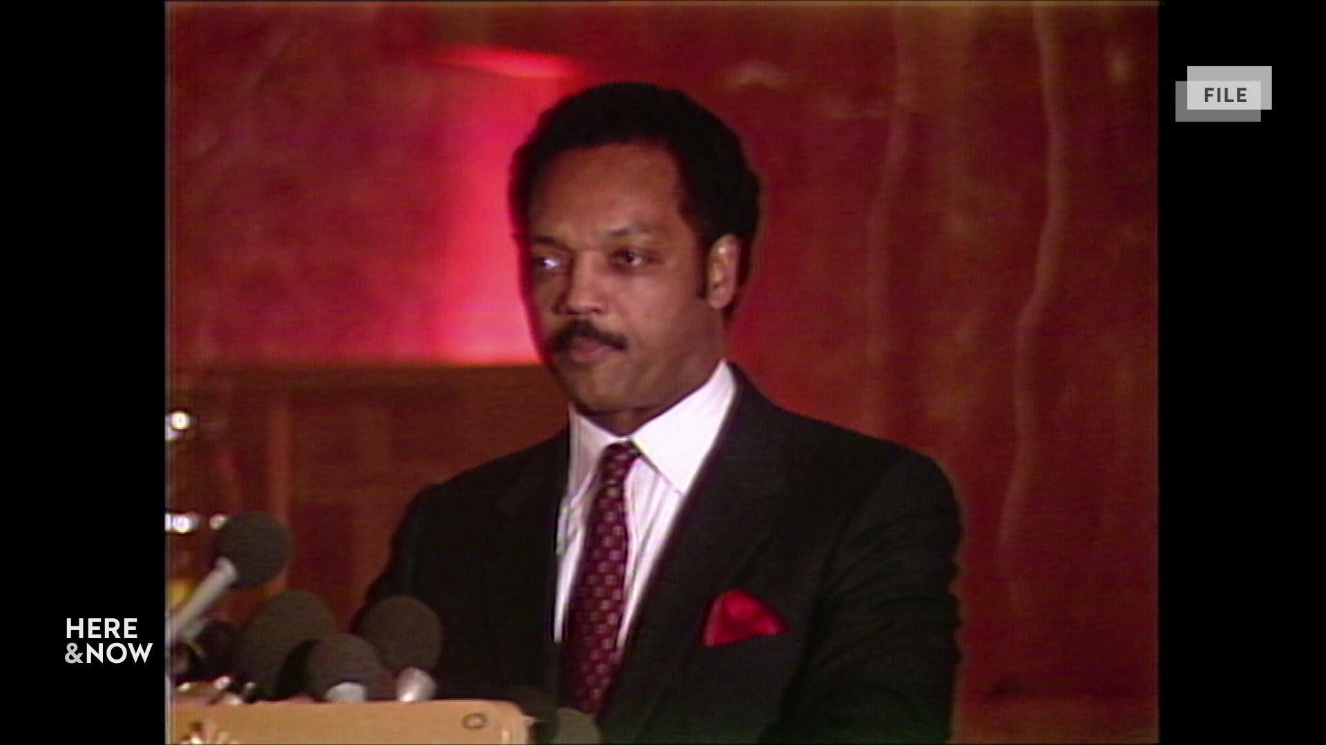A still image shows archival footage of Rev. Jesse Jackson standing in front of a podium A still image shows archival footage of Rev. Jesse Jackson standing in front of a podium