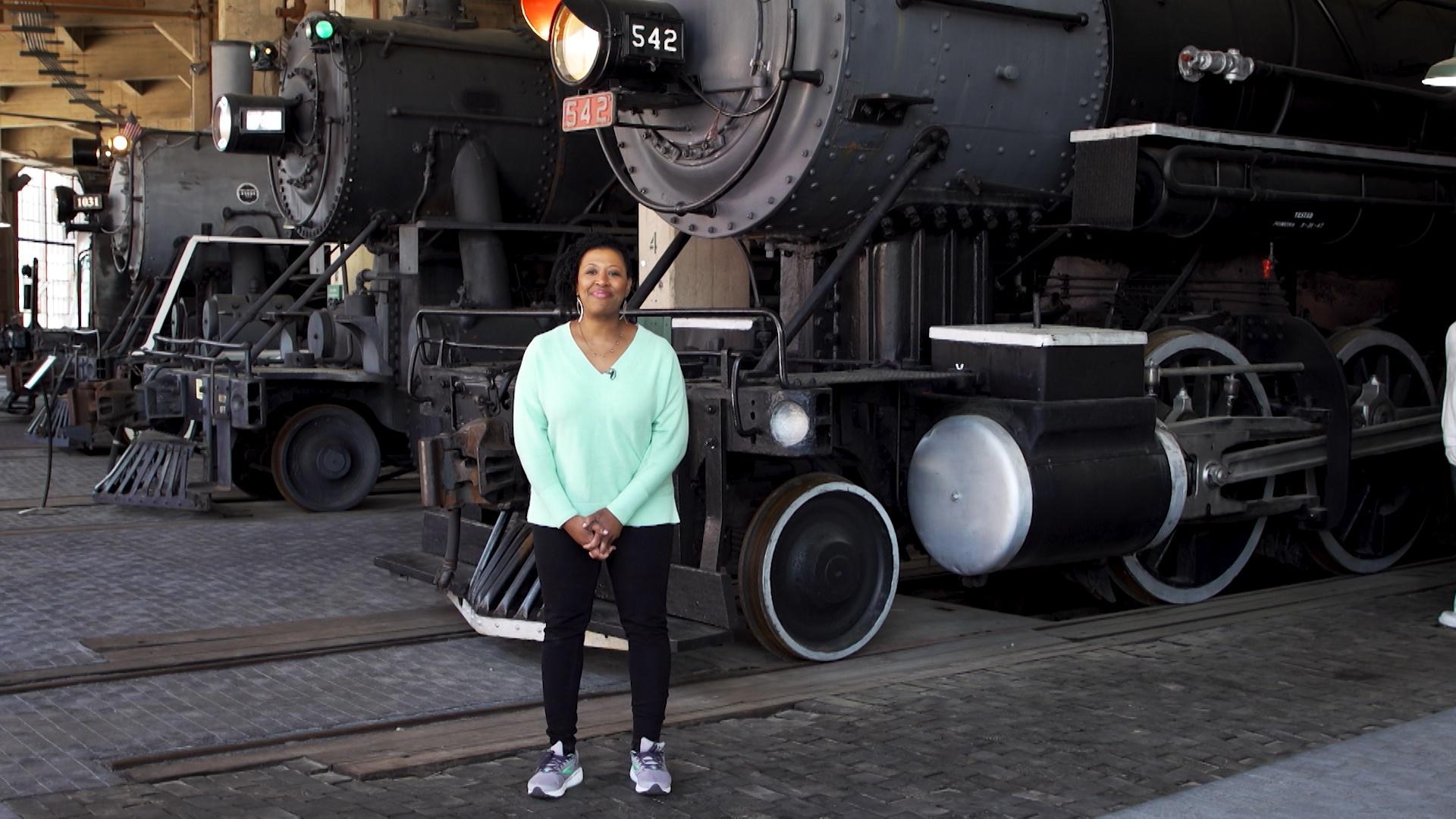 Host Deborah Holt Noel stands in front of a classic train from NC Weekend on PBS
