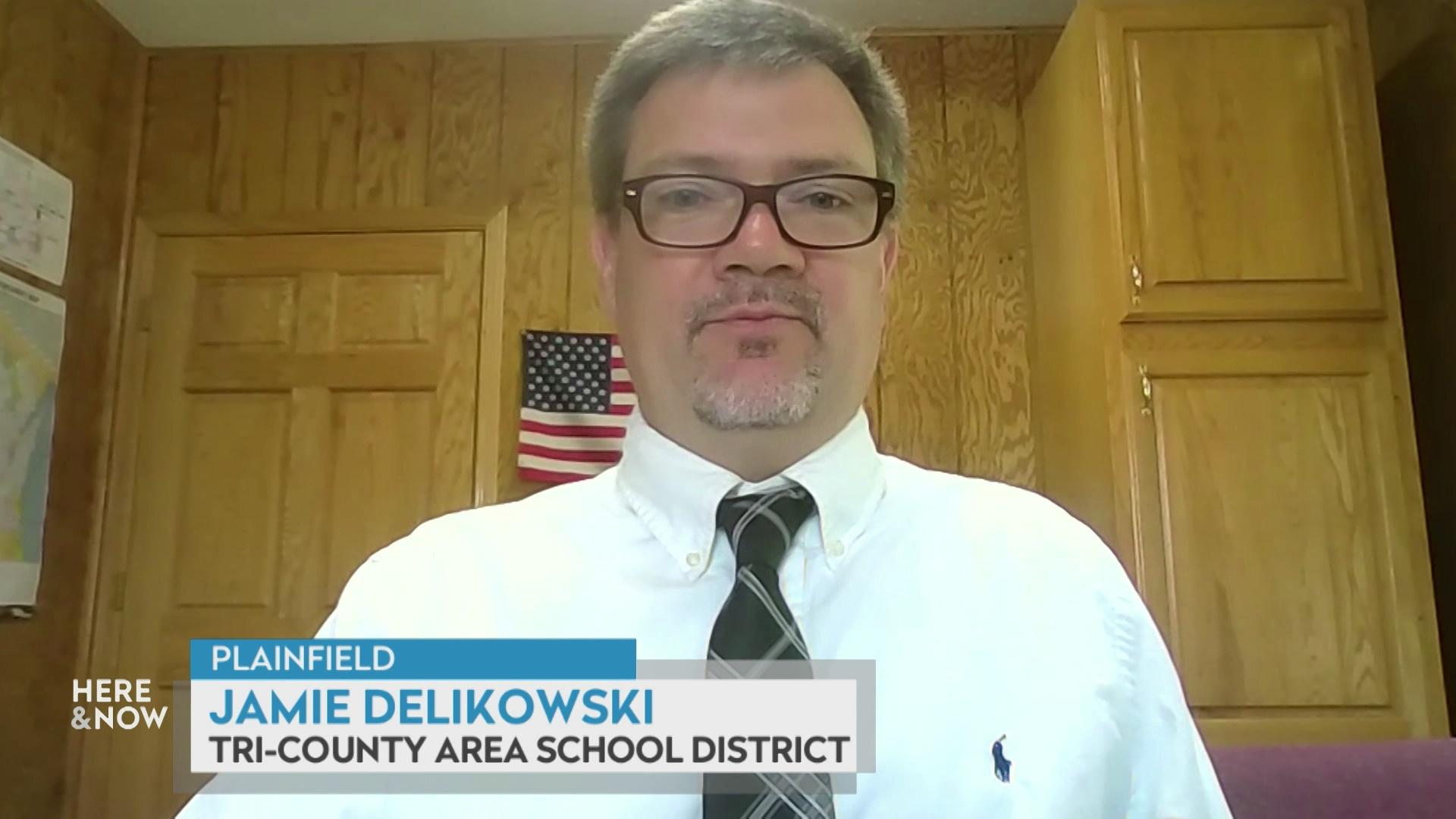 A still image from a video shows Jamie Delikowski seated in front of wooden walls and door with a graphic at bottom reading 'Plainfield,' 'Jamie Delikowski' and 'Tri-County Area School District.'