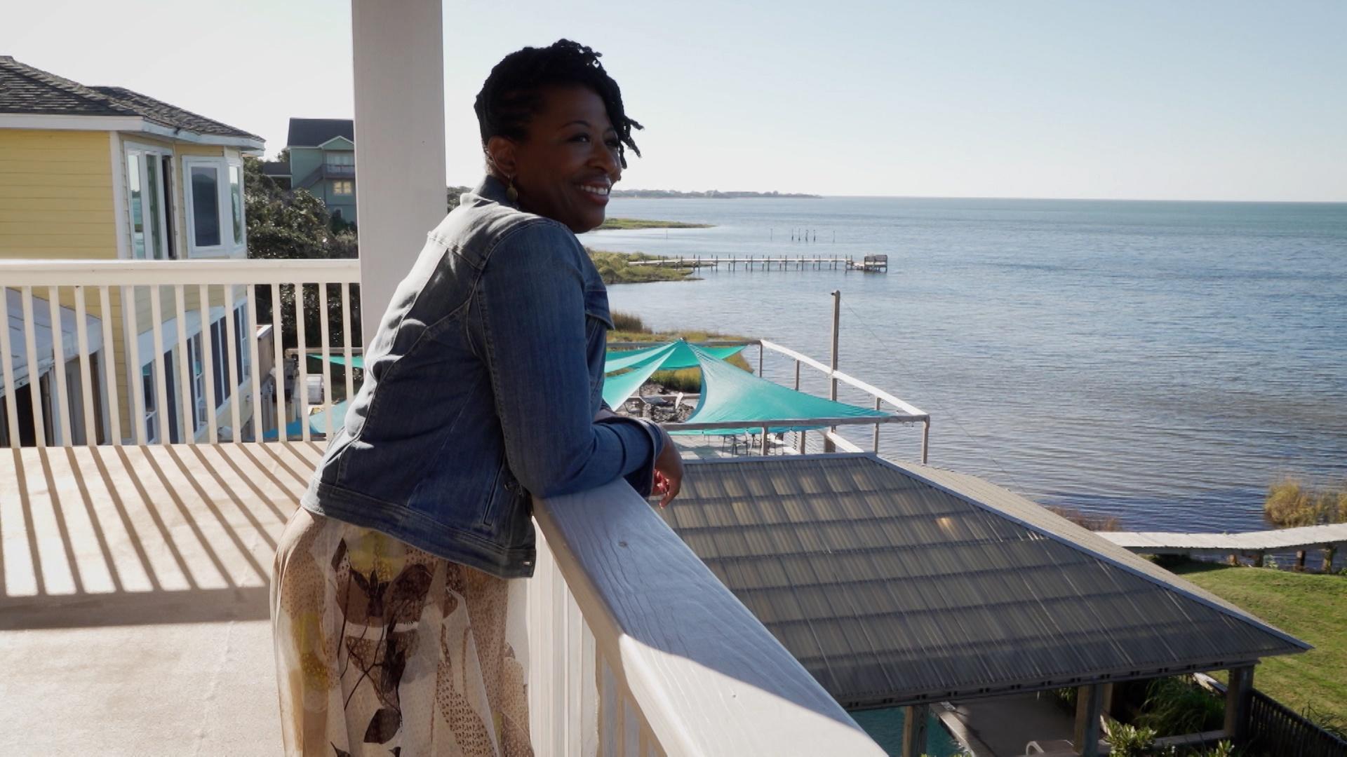 Host of NC Weekend Deborah Holt Noel on a balcony looking out over the Pamlico Sound.