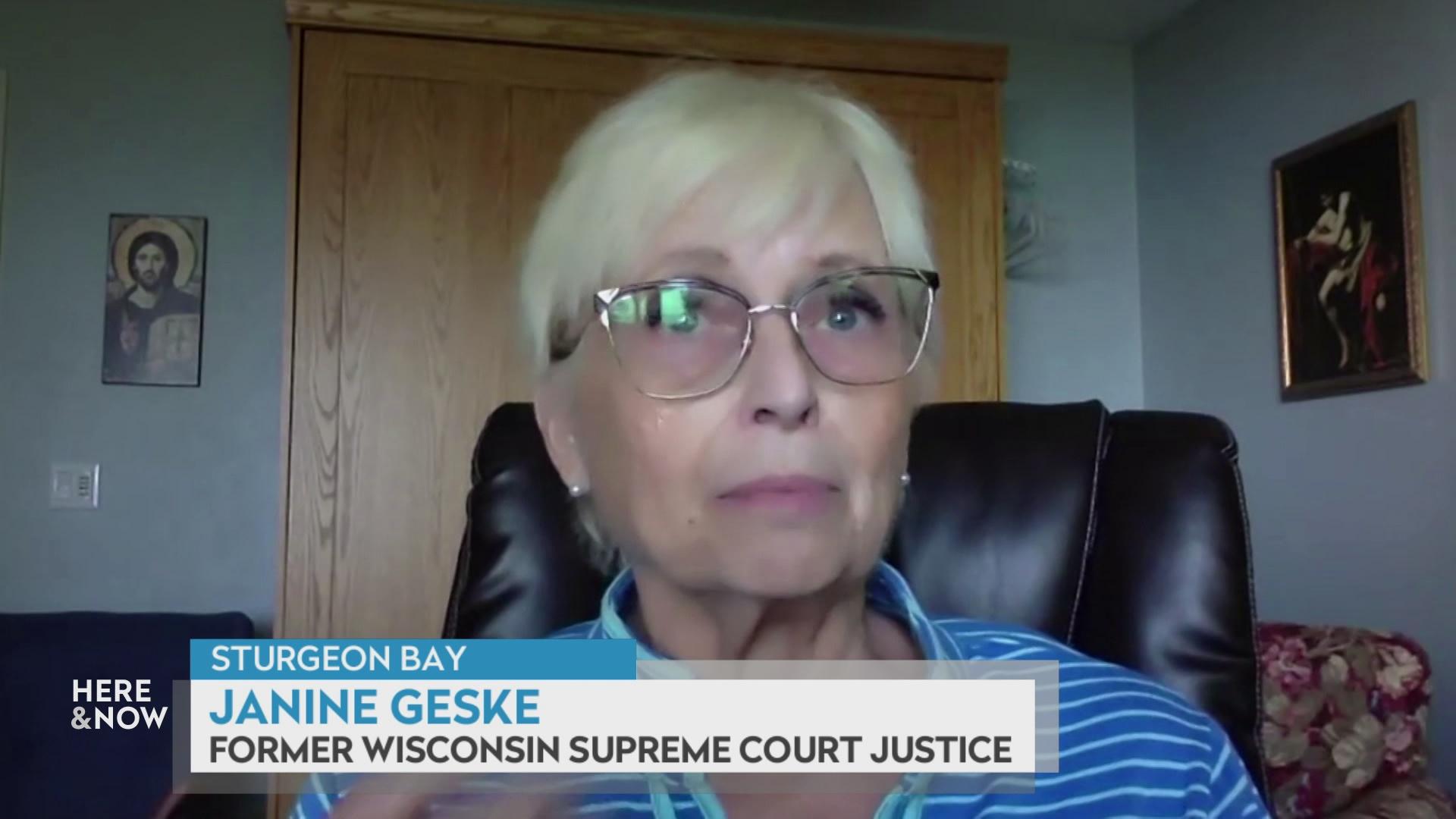 A still image from a video shows Janine Geske seated in front of a wooden door and blue wall with framed art with a graphic at bottom reading 'Sturgeon Bay,' 'Janine Geske' and 'Former Wisconsin Supreme Court Justice.'