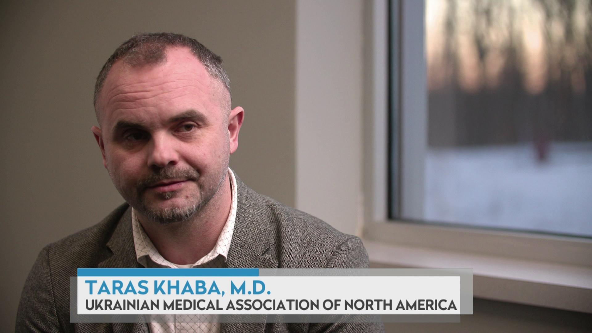 A still image from a video shows Taras Khaba sitting in a room with a window behind his left shoulder, with a graphic at bottom reading 'Taras Khaba, M.D.' and 'Ukrainian Medical Association of North America.'