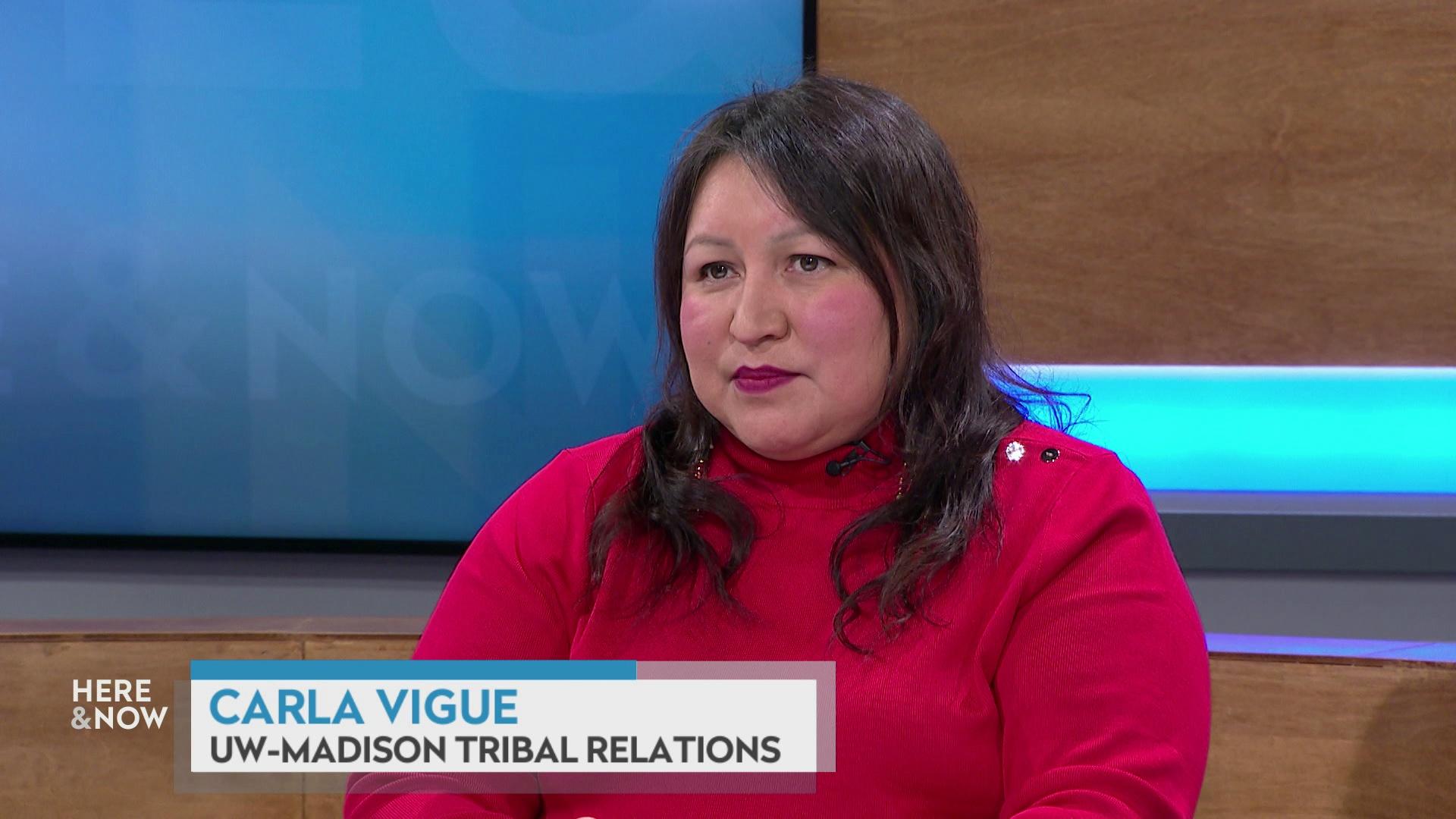 A still image shows Carla Vigue seated at the 'Here & Now' set featuring wood paneling, with a graphic at bottom reading 'Carla Vigue' and 'UW-Madison Tribal Relations.'