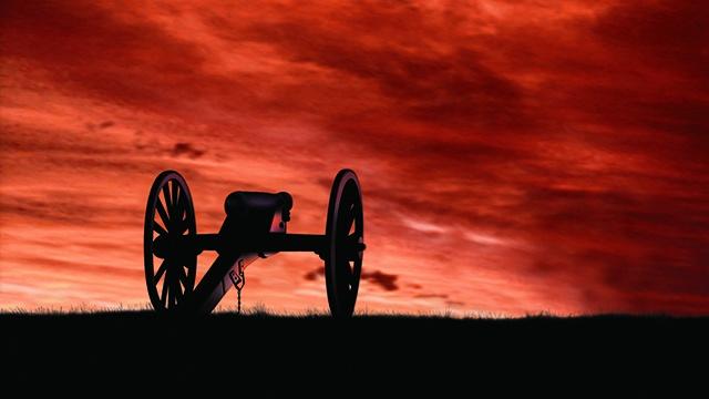 cannon on the field silhouetted against red sunset