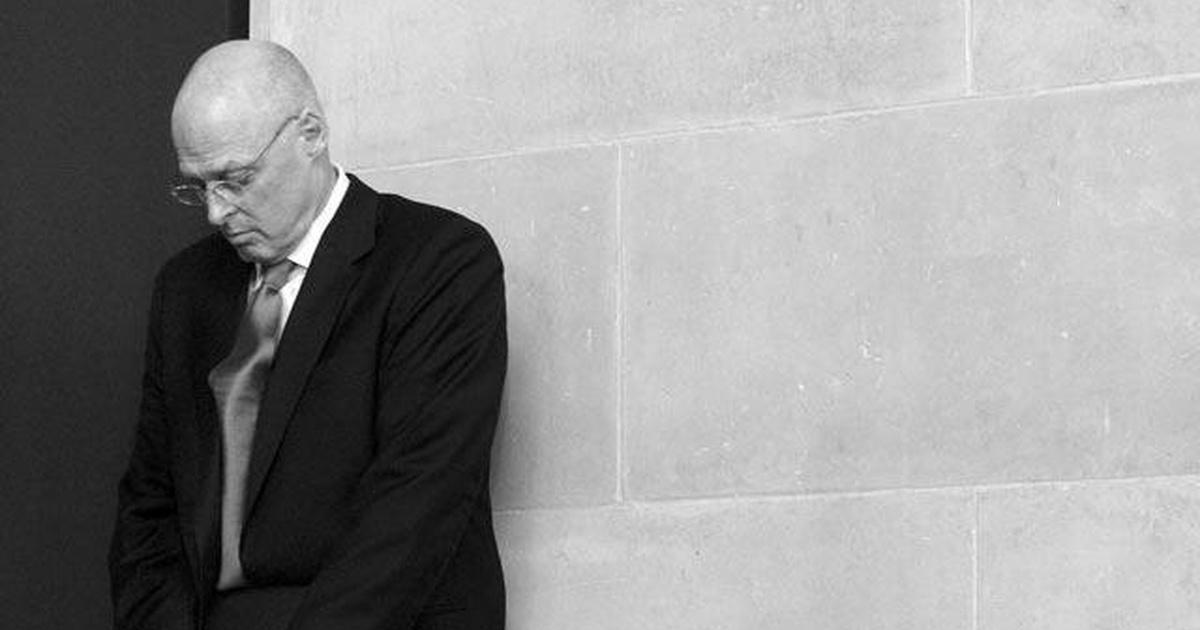 Businessman leaning against a wall and looking down