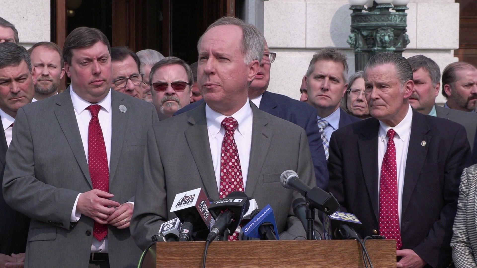 A still image from a video shows Robin Vos speaking into podium microphones and Republican members of the Wisconsin Assembly standing behind him.