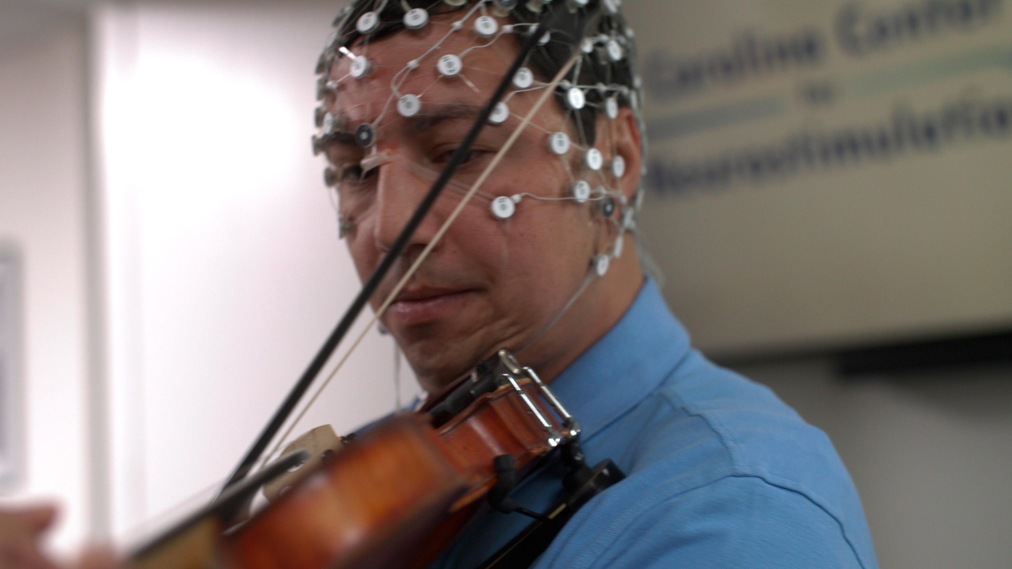 A person playing a violin with a mesh neural hat on.