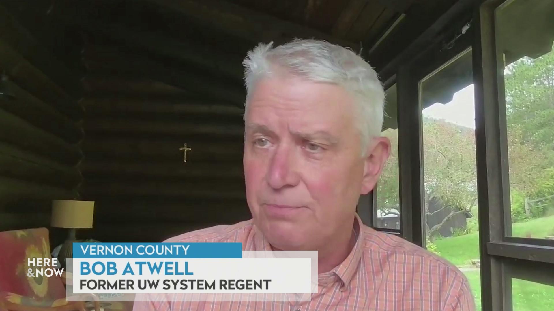 A still image from a video shows Bob Atwell seated indoors in front of a table and chair and glass door windows with a graphic at bottom reading 'Vernon County,' 'Bob Atwell' and 'Former UW System Regent.'