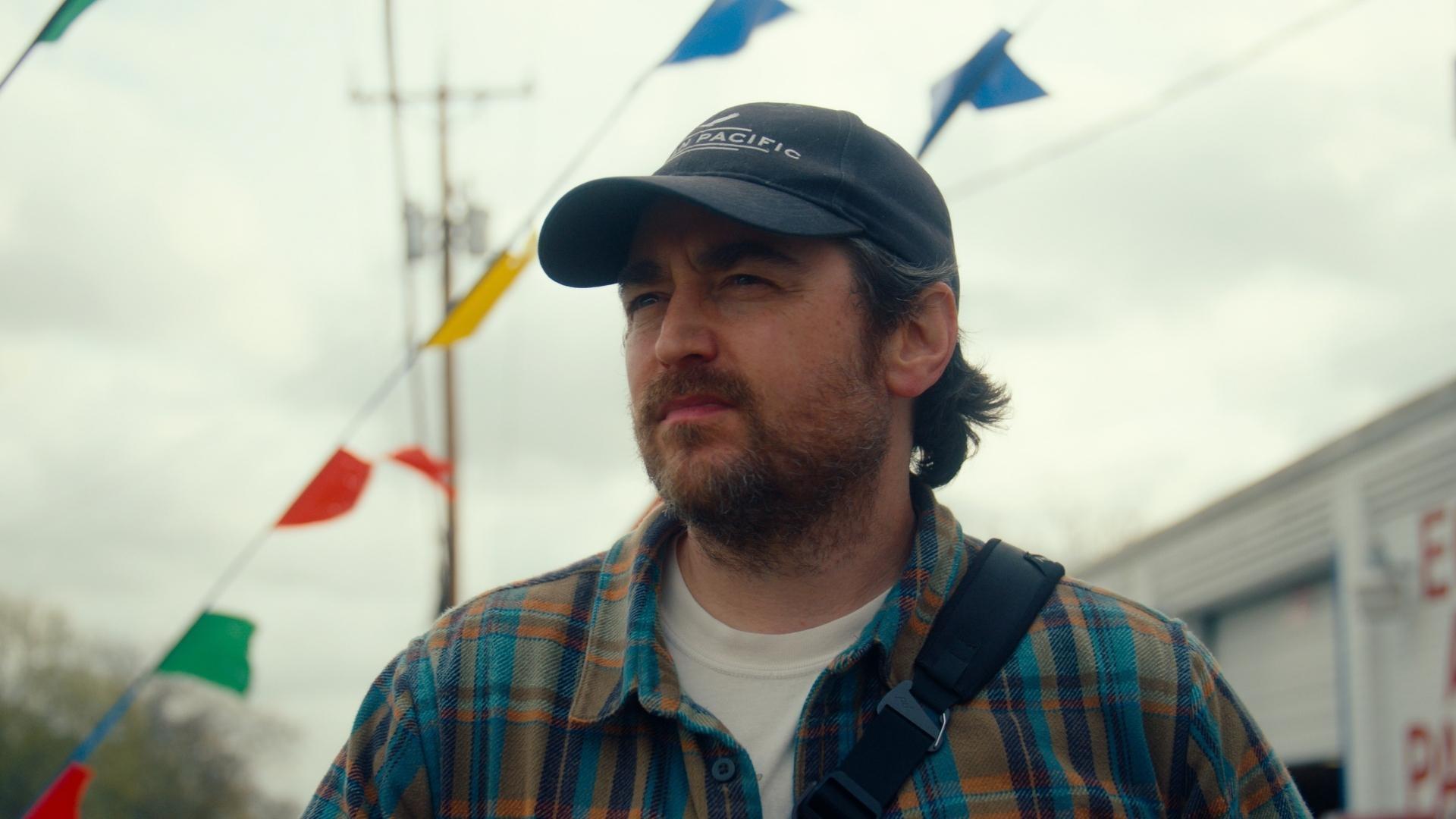 Photographer Ben Harris with a teal and orange flannel and navy blue baseball cap on.