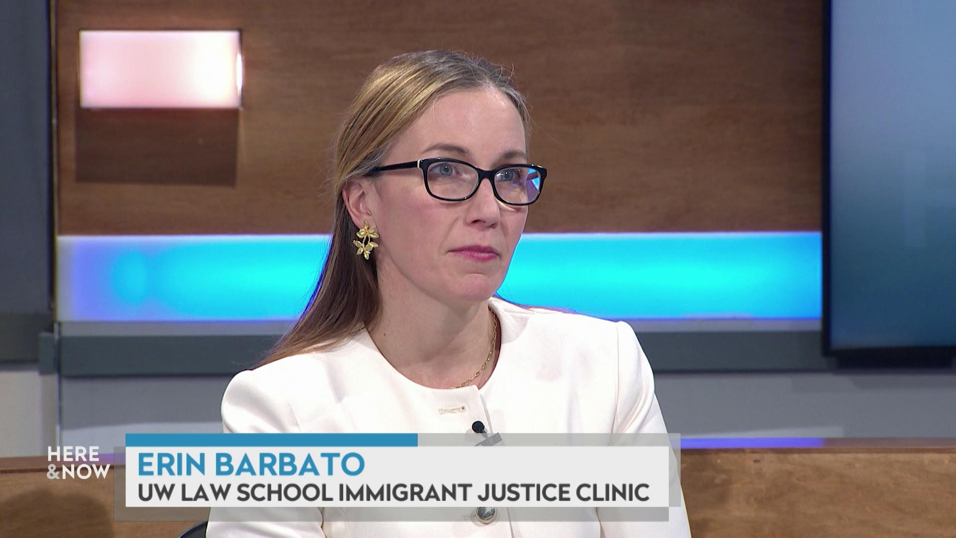 A still image shows Erin Barbato seated at the 'Here & Now' set featuring wood paneling, with a graphic at bottom reading 'Erin Barbato' and 'UW Law School Immigrant Justice Clinic.'