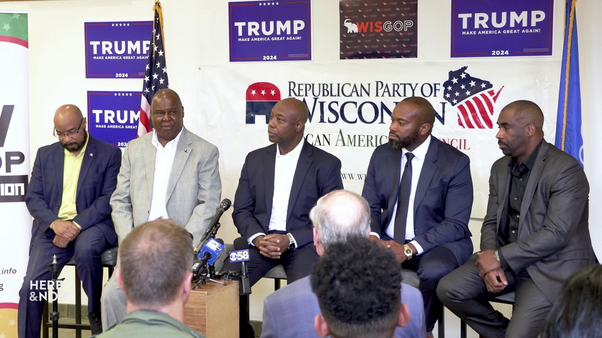 Five Black Republicans, including Senator Tim Scott, sit on chairs with Trump posters on the wall in the background.