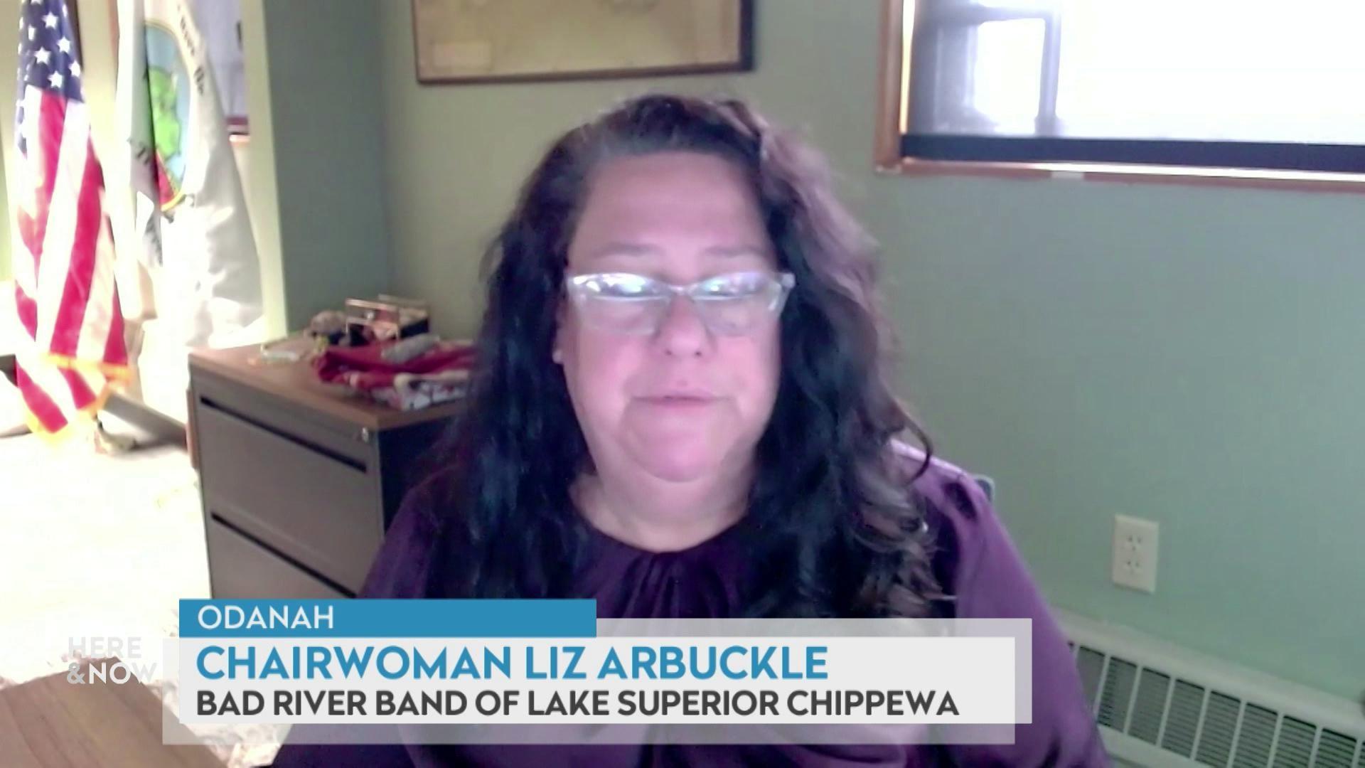 A still image shows Liz Arbuckle seated in front of a green wall, the American flag and the Bad River Band of Lake Superior Chippewa Indians flag, with a graphic at the bottom that reads 'Odanah,' 'Chairwoman Liz Arbuckle' and 'Bad River Band of Lake Superior Chippewa.'