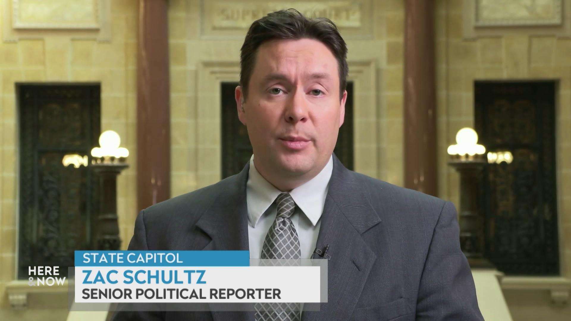  A still image from a video shows Zac Schultz standing in front of the Wisconsin Supreme Court chambers at the state Capitol with a graphic at bottom reading 'Zac Schultz' and 'Senior Political Reporter.'
