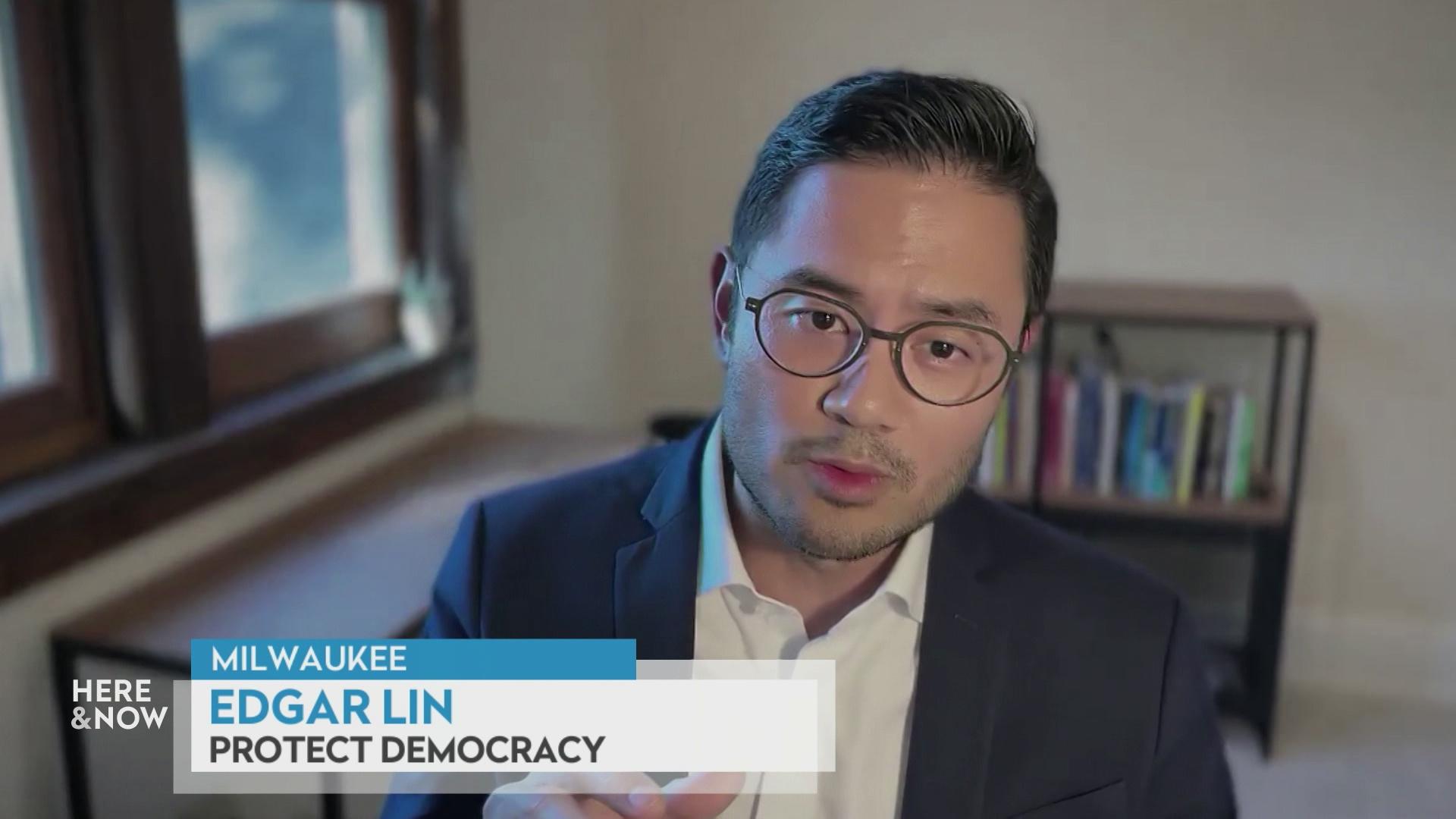 A still image from a video shows Edgar Lin  seated in front of a blurred background with a graphic at bottom reading 'Milwaukee,' 'Edgar Lin' and 'Protect Democracy.'