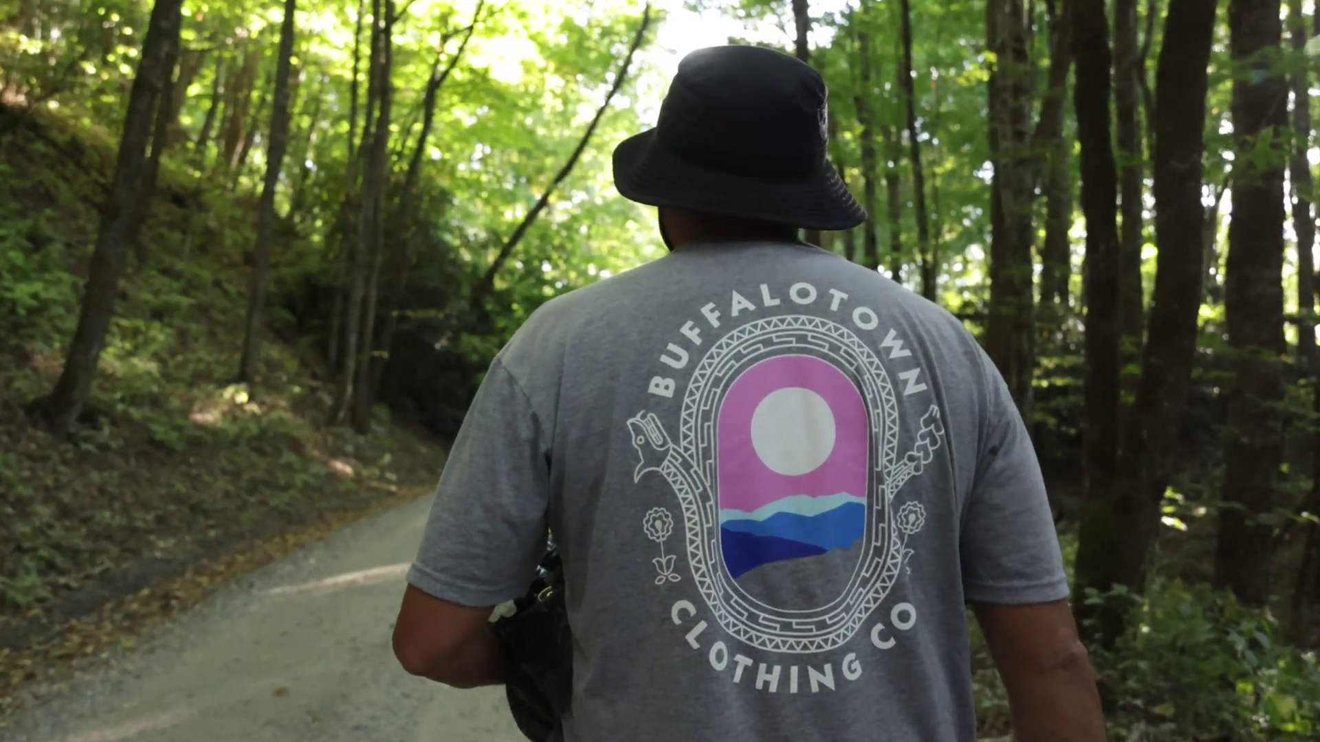Luke Swimmer walking through the woods wearing a Buffalotown t-shirt.