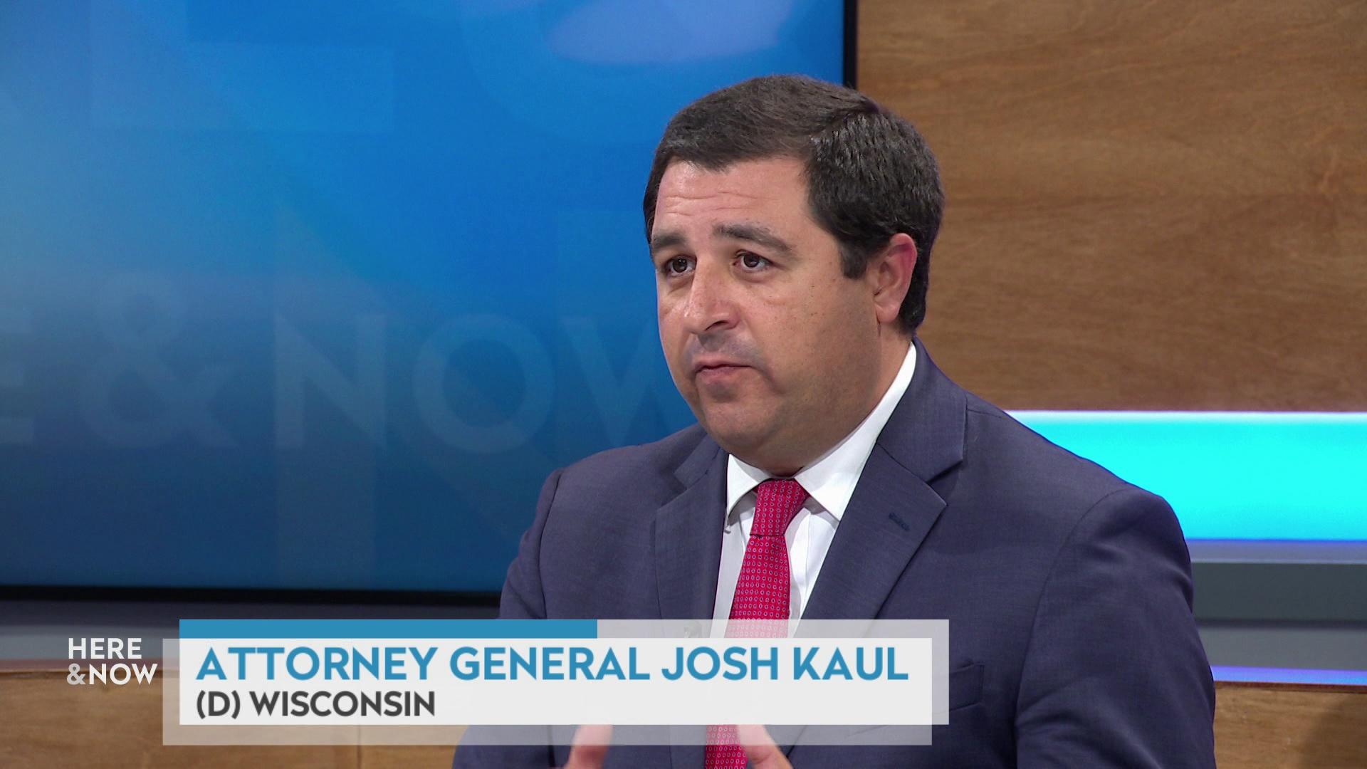 A still image shows Josh Kaul seated at the 'Here & Now' set featuring wood paneling, with a graphic at bottom reading 'Attorney General Josh Kaul' and '(D) Wisconsin.'