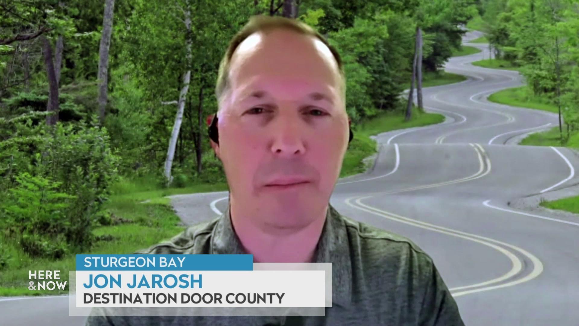 A still image shows Jon Jarosh superimposed on an image of a winding road in a forest, with a graphic at the bottom that reads 'Sturgeon Bay,' 'Jon Jarosh' and 'Destination Door County.'
