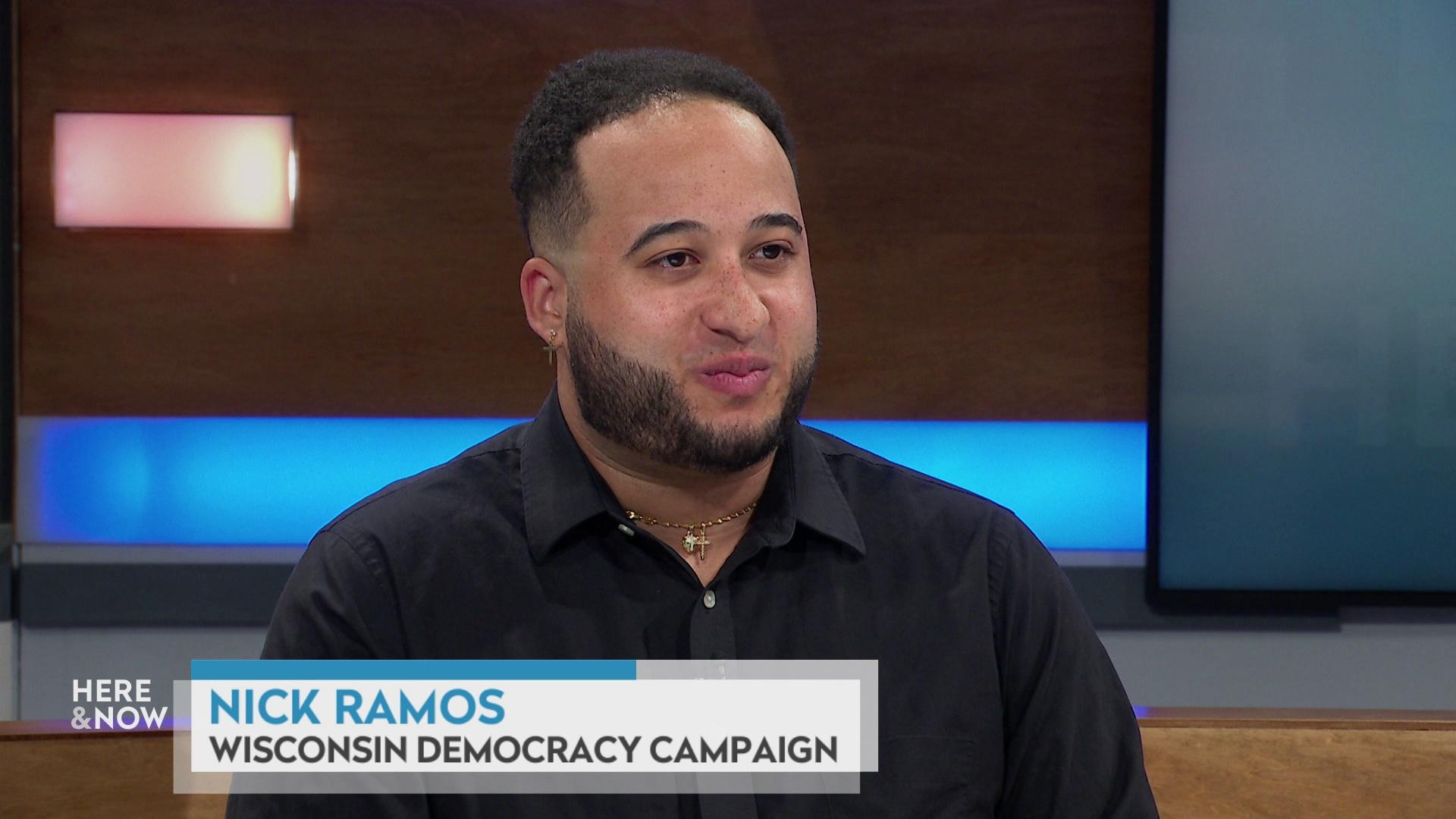 Nick Ramos sits at the 'Here & Now' set featuring wood paneling, with a graphic at bottom reading 'Nick Ramos' and 'Wisconsin Democracy Campaign.'