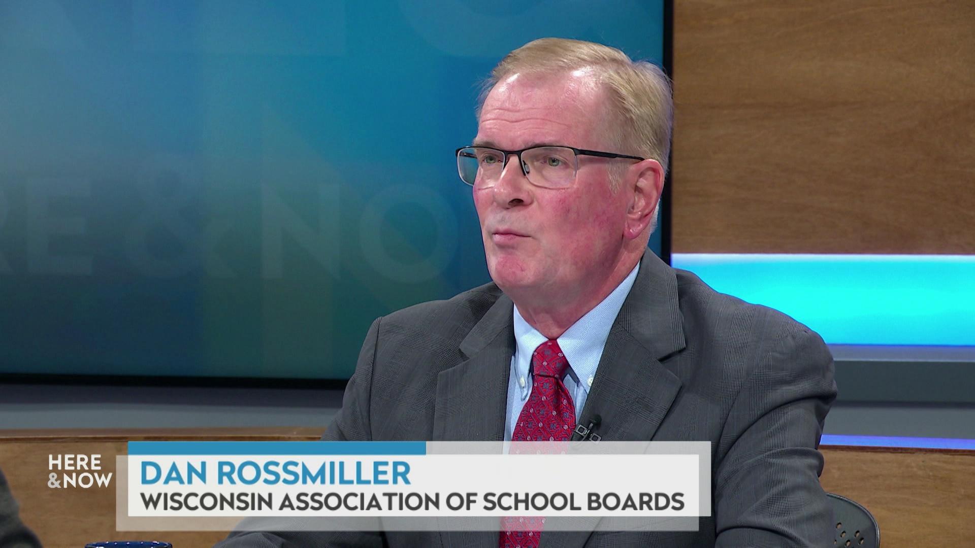 A still image shows Dan Rossmiller seated at the 'Here & Now' set featuring wood paneling, with a graphic at bottom reading 'Dan Rossmiller' and 'Wisconsin Association of School Boards.'