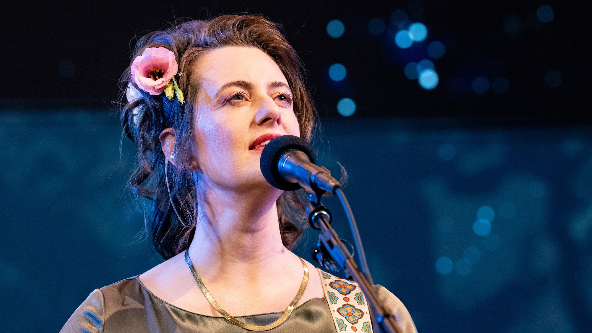 Singer-songwriter Skylar Gudasz singing into a microphone.