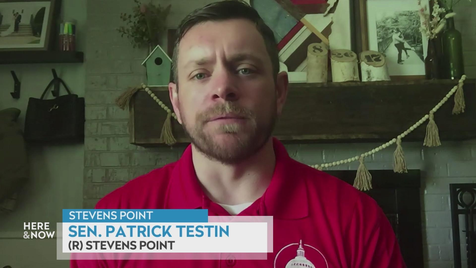 A still image from a video shows Patrick Testing seated in front of a white brick fire place with a graphic at bottom reading 'Stevens Point,' 'Sen. Patrick Testin' and '(R) Stevens Point.'